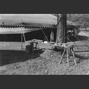 Wash-bench and wash-pans under tree beside tent Ringling Bros