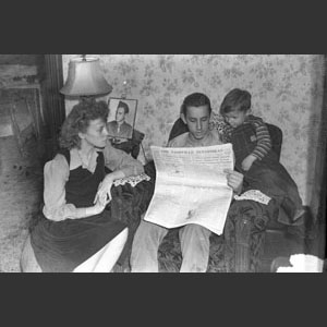 Young couple with little boy gathered around chair reading