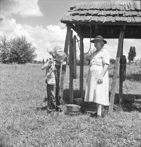 Aunt Minnie standing beside well - Robert getting drink